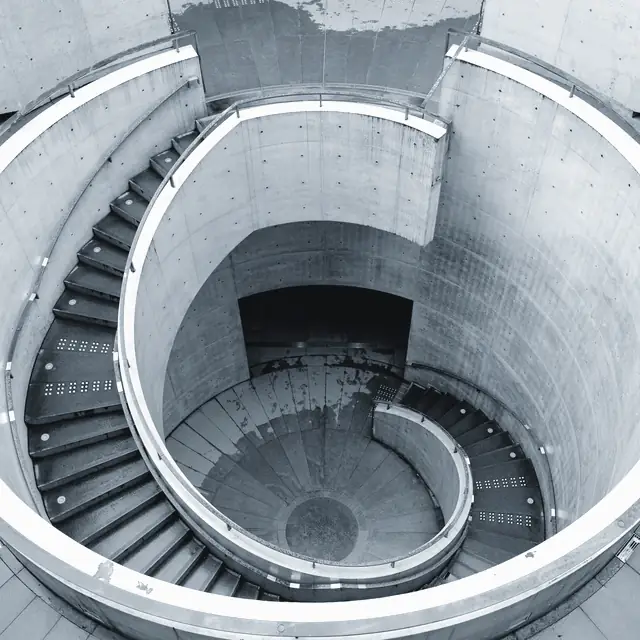 Escada em espiral de concreto aparente vista de cima.